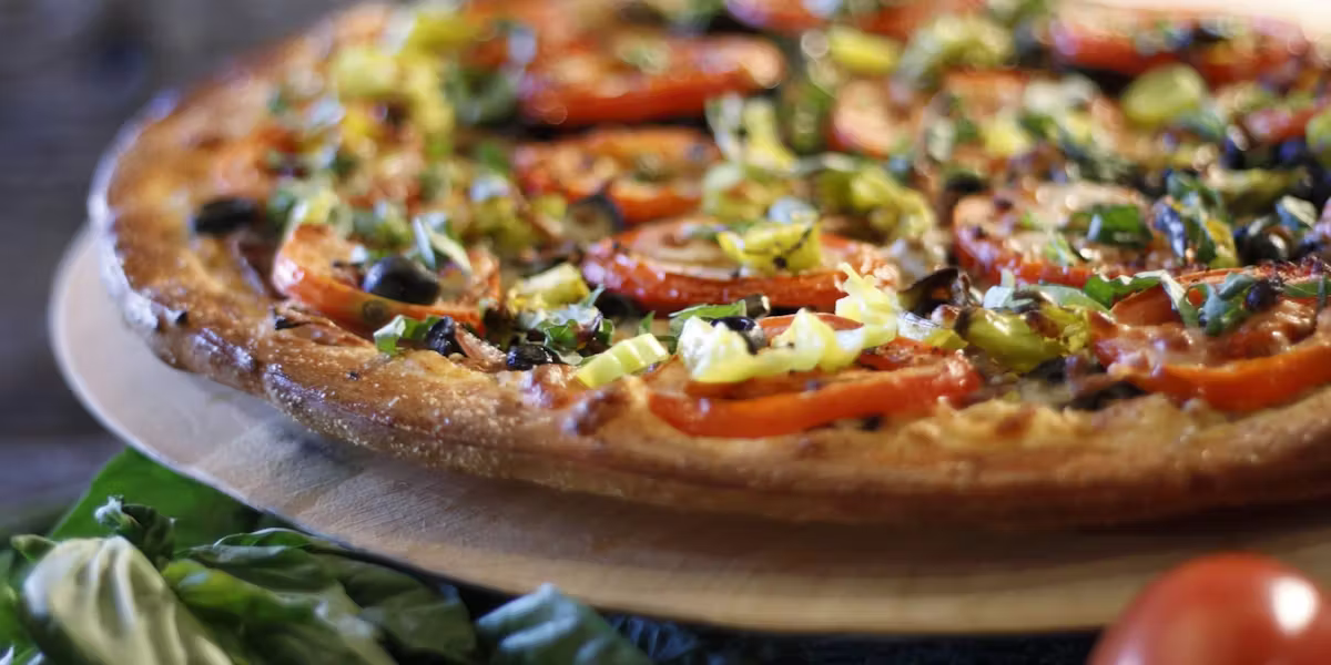 Extreme Pizza loaded with fresh roasted peppers, olives, artichokes and herbs
